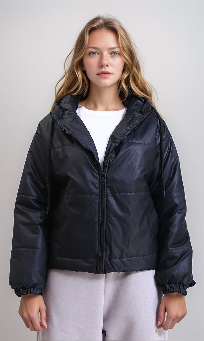 Woman wearing a black puffer jacket over a white shirt on a plain background