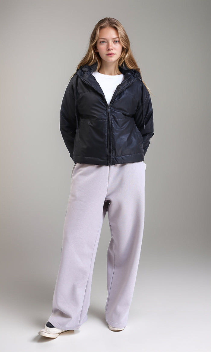 Person wearing a black jacket and light gray pants on a plain background