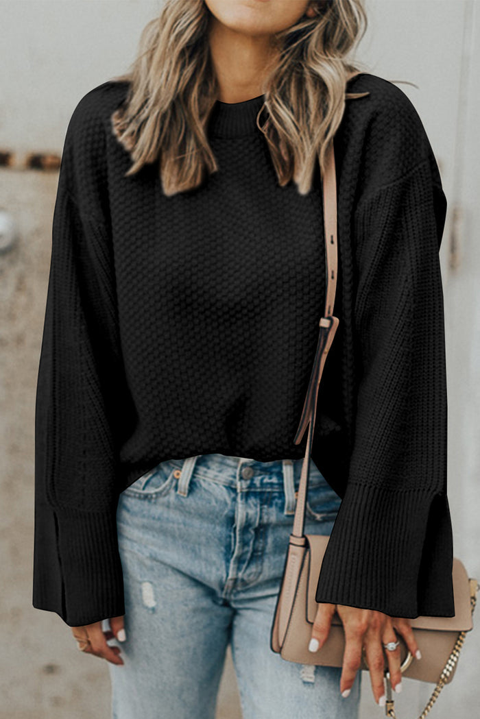 Pull ample noir en tricot texturé uni, manchette fendue*