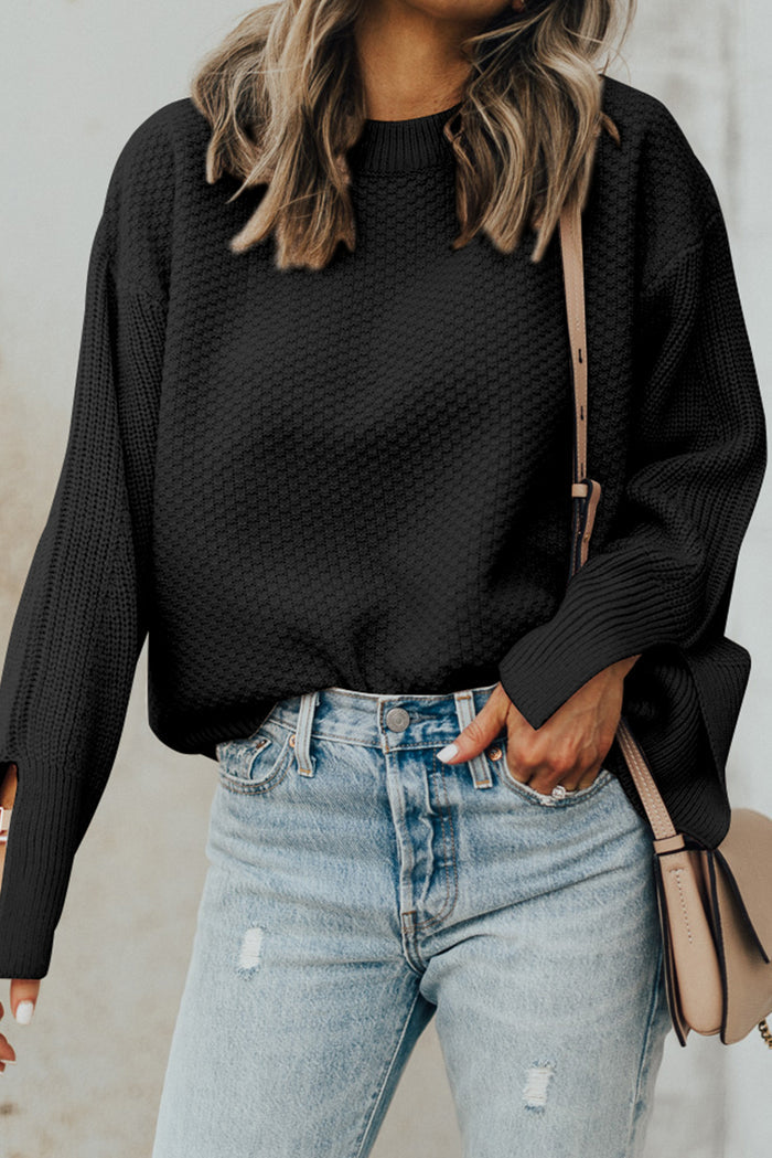 Pull ample noir en tricot texturé uni, manchette fendue*