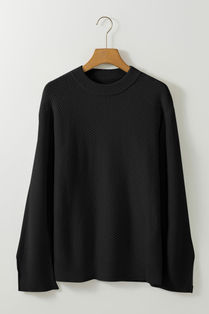 Pull ample noir en tricot texturé uni, manchette fendue*