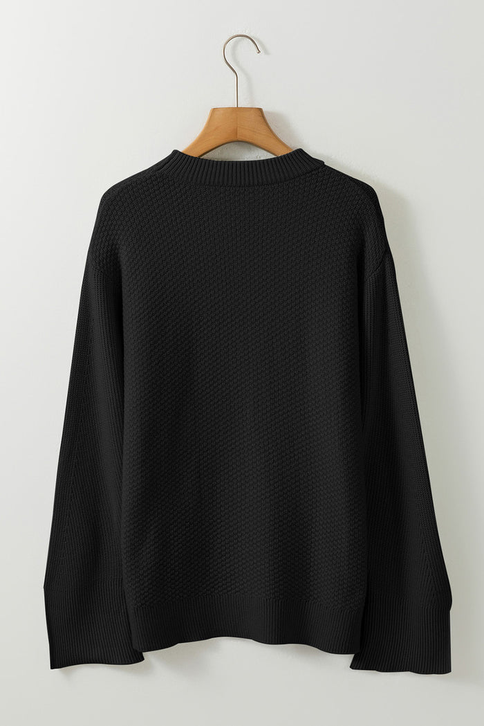 Pull ample noir en tricot texturé uni, manchette fendue*