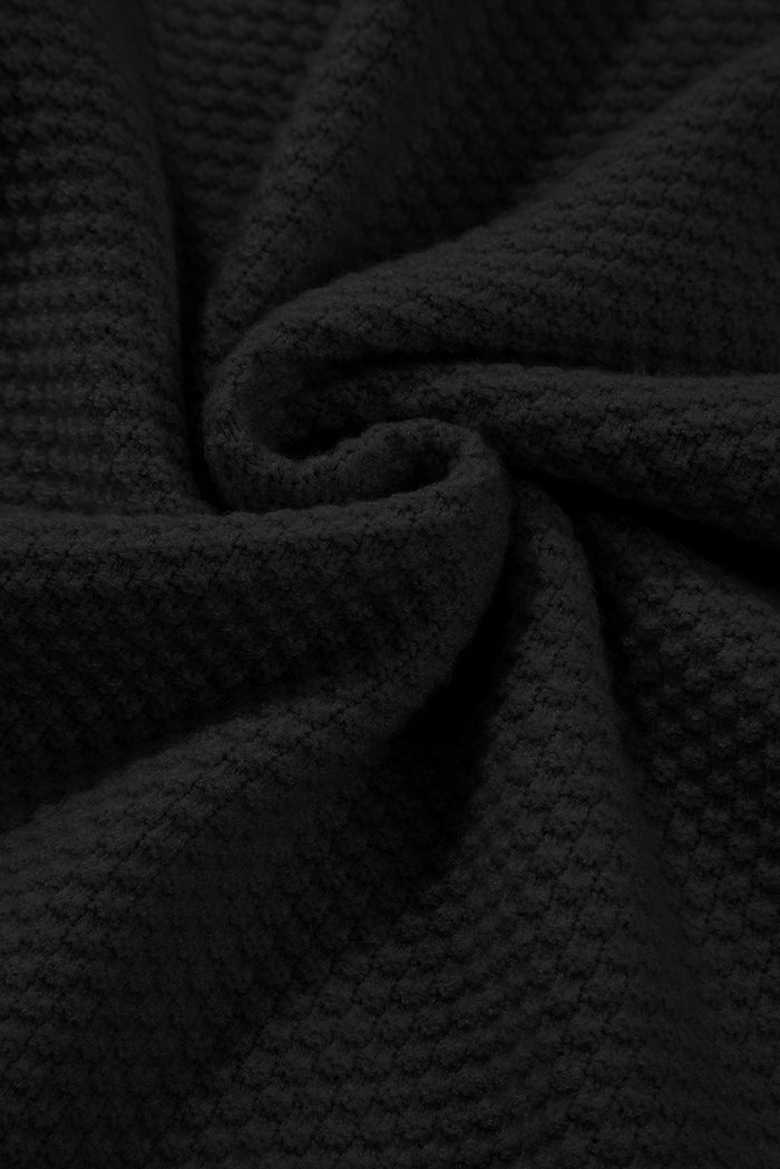 Pull ample noir en tricot texturé uni, manchette fendue*