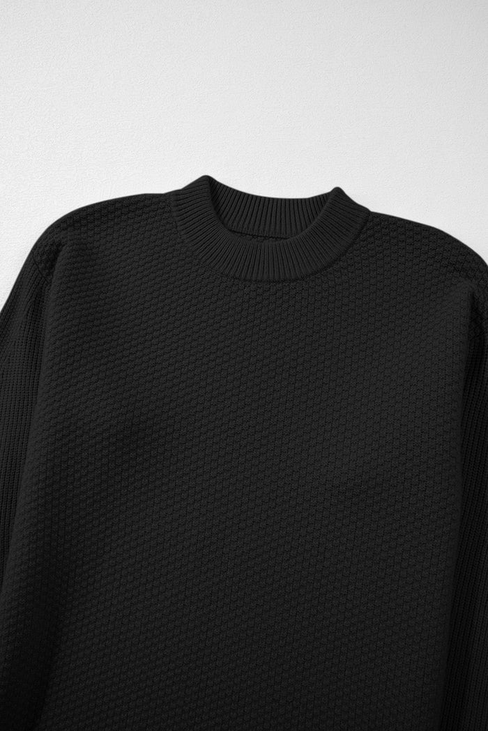Pull ample noir en tricot texturé uni, manchette fendue*