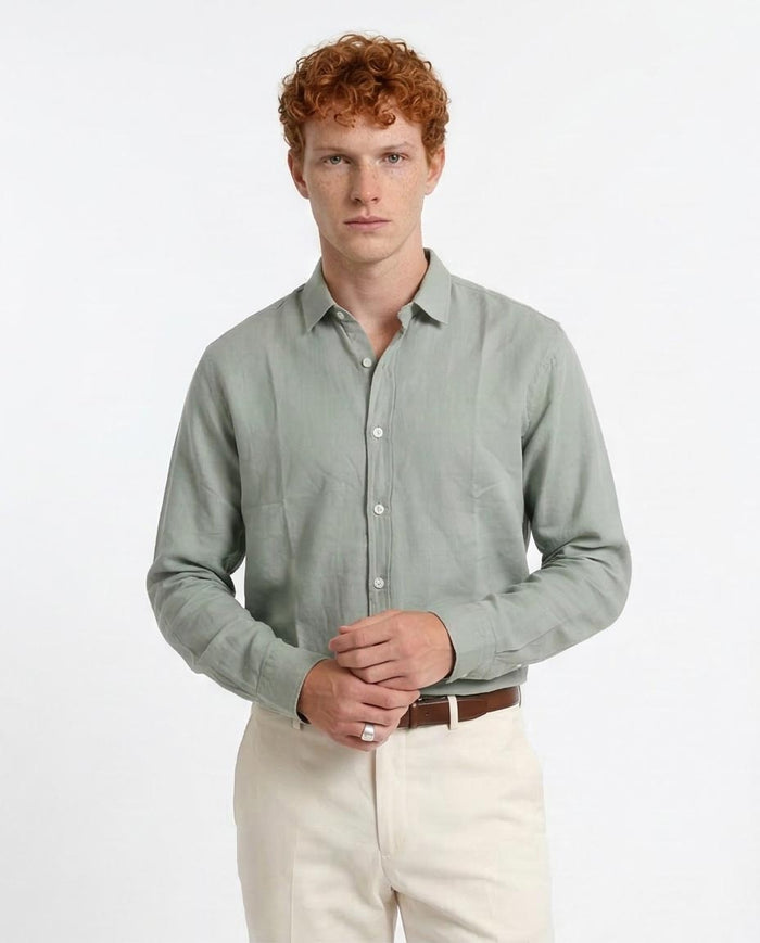 Man wearing a light green shirt and white pants on a plain background