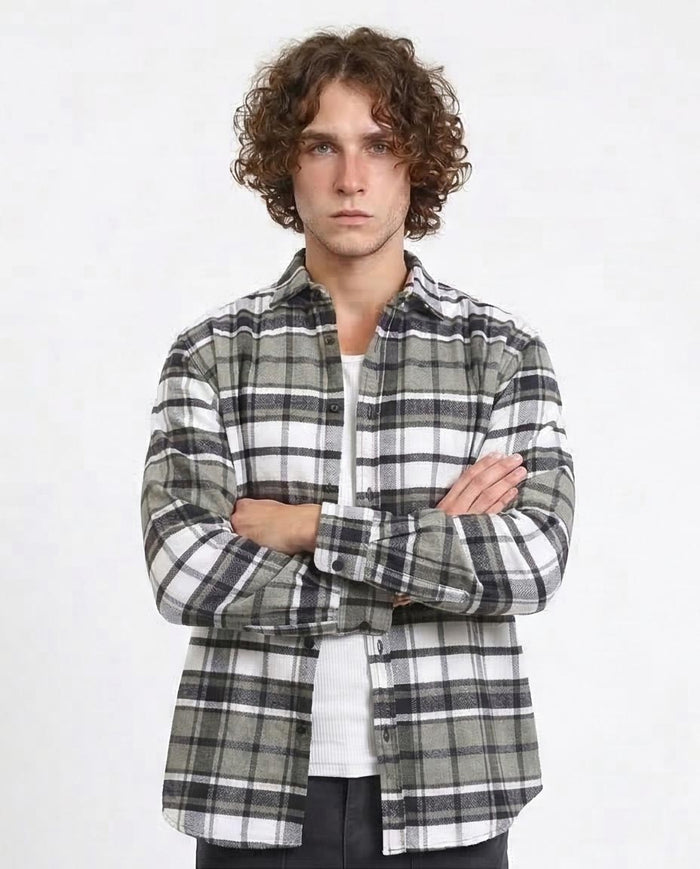 Man wearing a plaid shirt with arms crossed on a white background