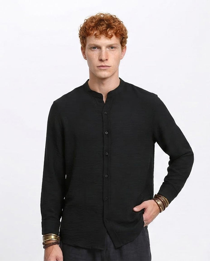 Man wearing a black long-sleeve shirt with a plain background
