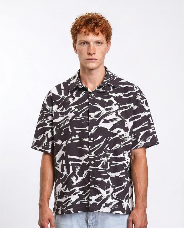 Man wearing a black and white patterned shirt on a plain background