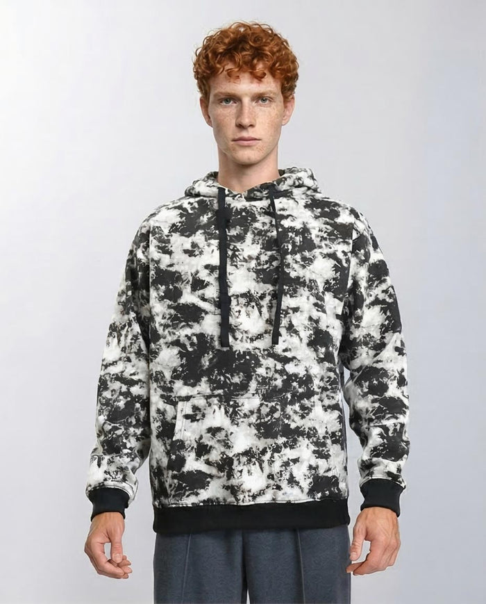 Man wearing a camouflage hoodie against a plain background