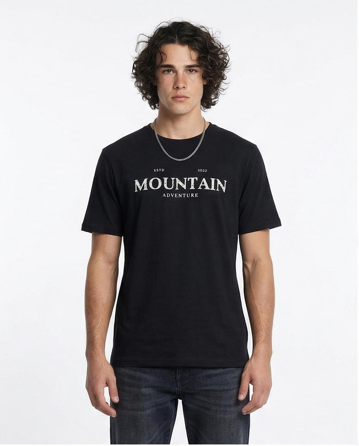 Man wearing a black t-shirt with 'Mountain Adventure' text on a white background