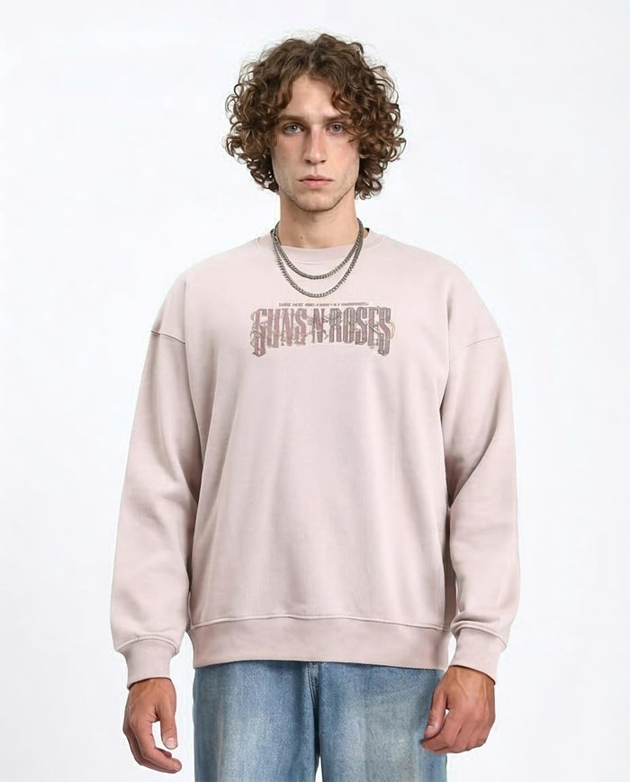 Person wearing a beige 'Guns N' Roses' sweatshirt on a white background
