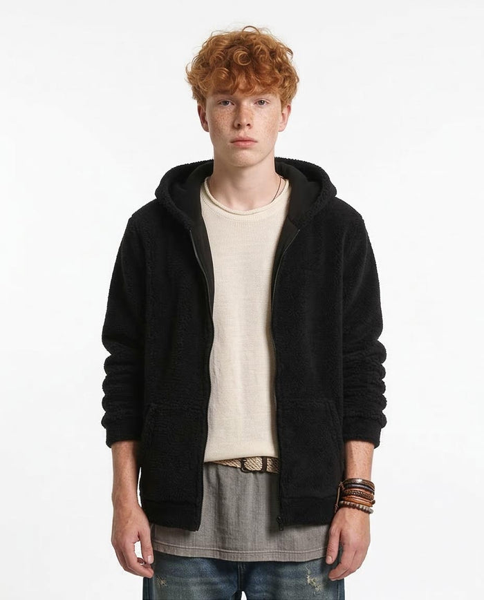 Person wearing a black hoodie over a beige shirt with a white background