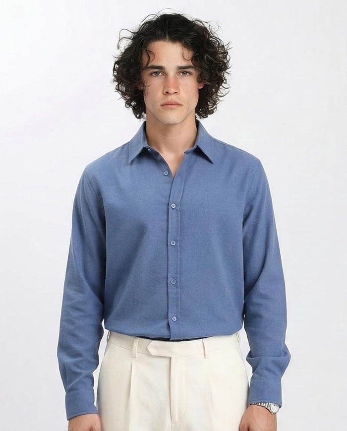 Man wearing a blue shirt and white pants on a plain background