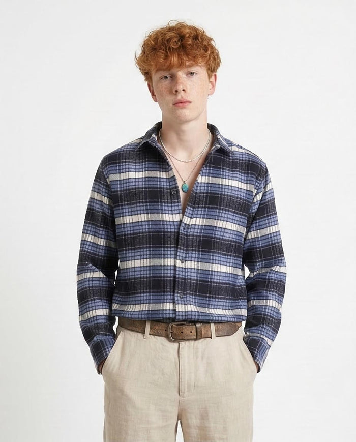 Person wearing a blue plaid shirt with a plain background