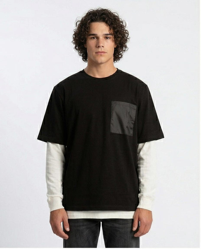 Man wearing a black and white layered shirt on a plain background