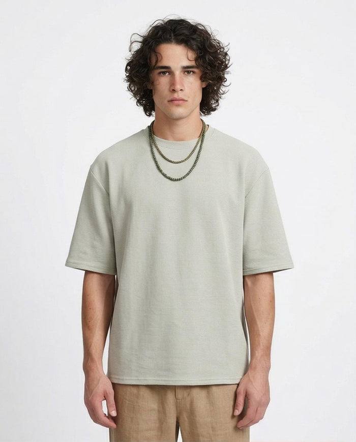 Man wearing a light green t-shirt and beige pants on a white background