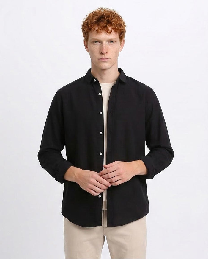 Man wearing a black shirt over a beige shirt on a white background