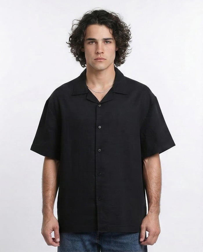 Man wearing a black short-sleeve button-up shirt against a white background