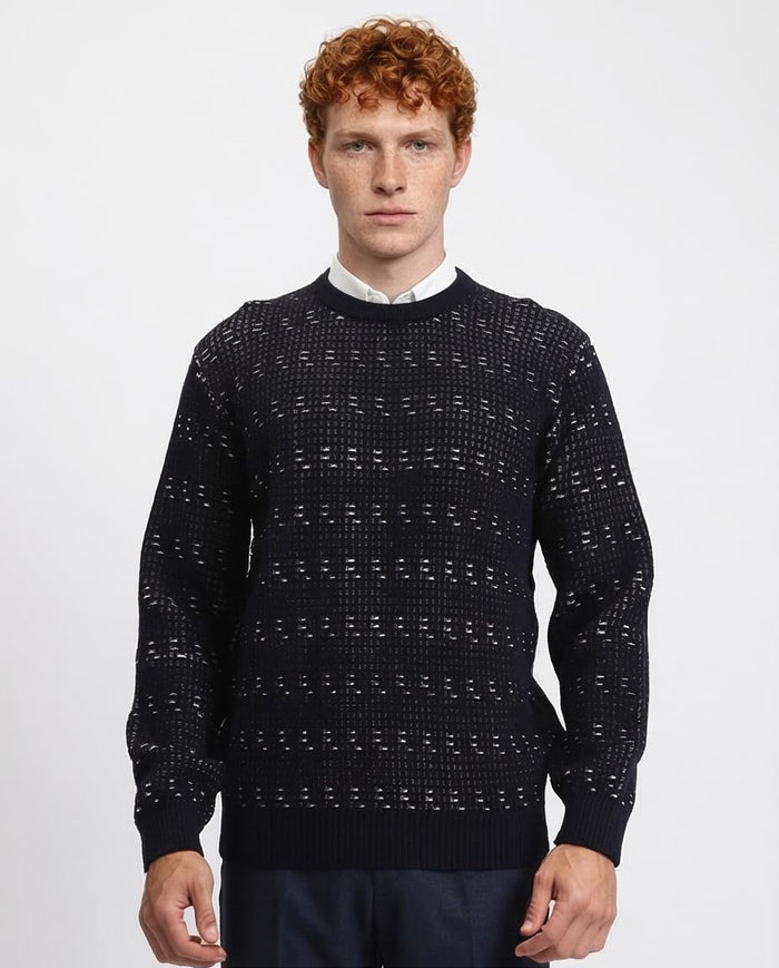 Man wearing a dark patterned sweater on a light gray background