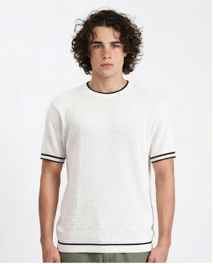 Man wearing a white textured t-shirt with black trim on a plain background
