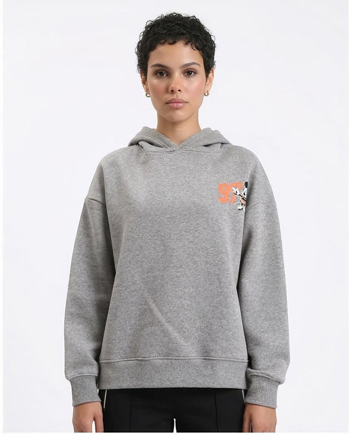 Person wearing a gray hoodie with a small logo on a white background