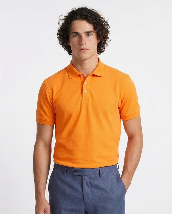 Man wearing an orange polo shirt and blue pants on a white background