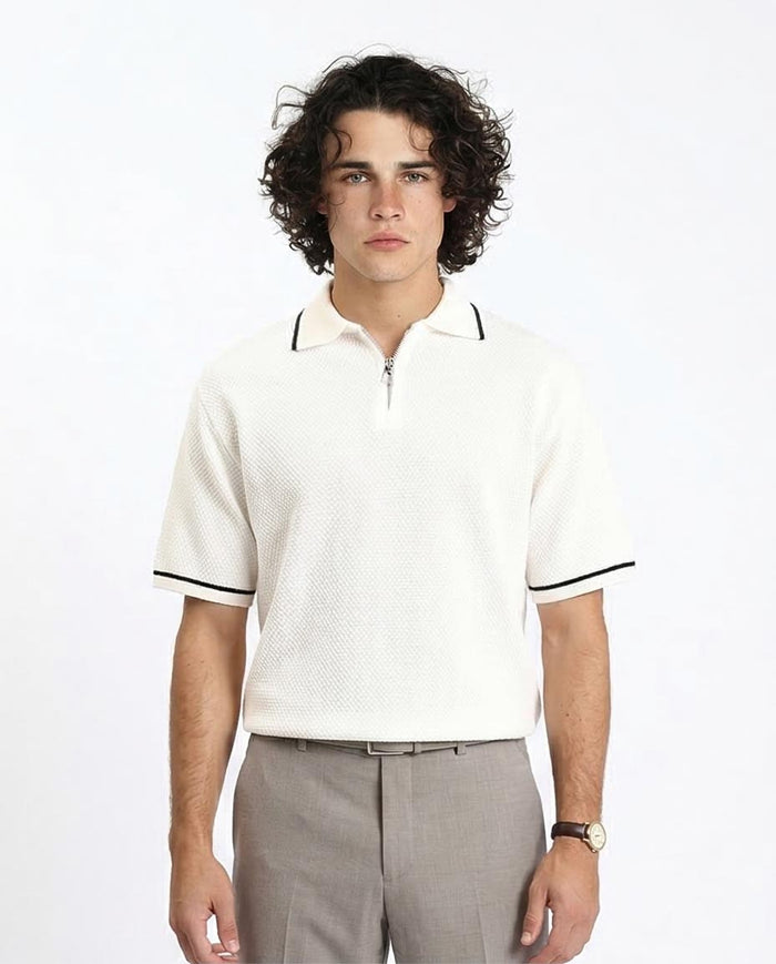 Man wearing a white polo shirt with black trim on a plain background