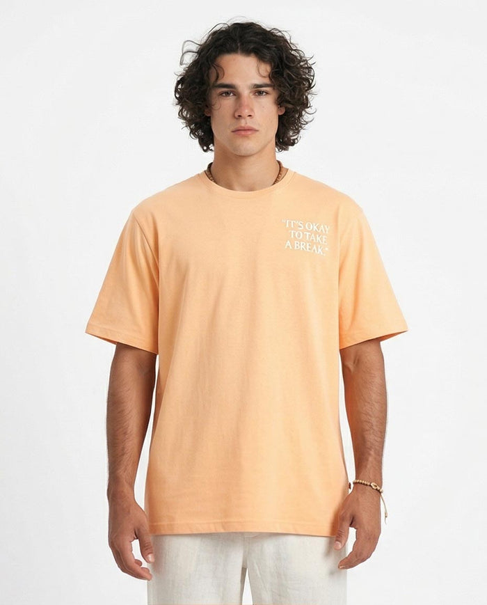 Man wearing a peach t-shirt with text on a white background