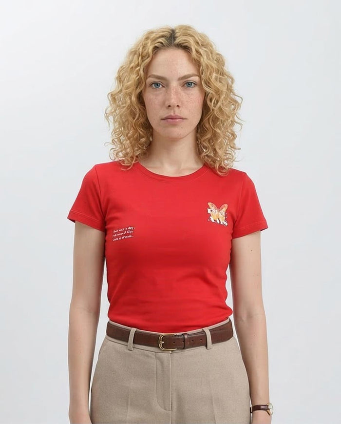 Woman wearing a red t-shirt with a small graphic and text on a plain background