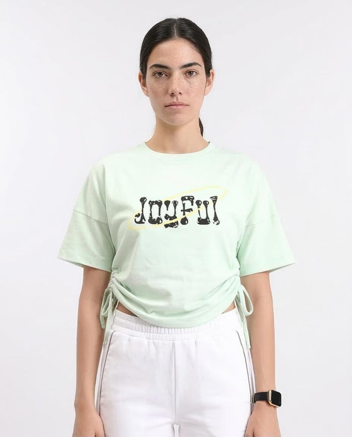 Woman wearing a light green t-shirt with 'JOYFUL' text on a white background