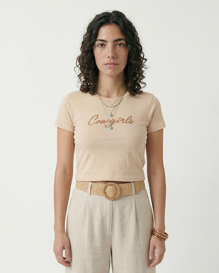 Woman wearing a beige t-shirt with 'Conscious' text, standing against a plain background