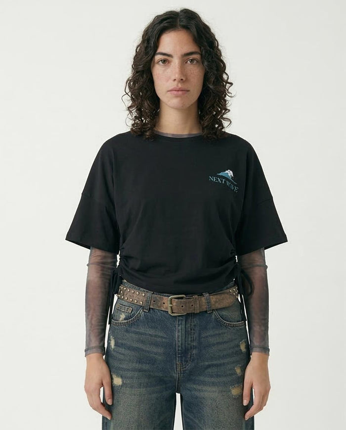 Person wearing a black t-shirt with a logo and blue jeans on a white background