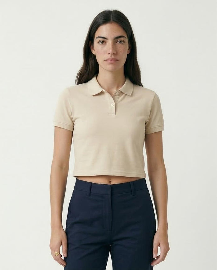 Woman wearing a beige cropped polo shirt and navy pants on a white background
