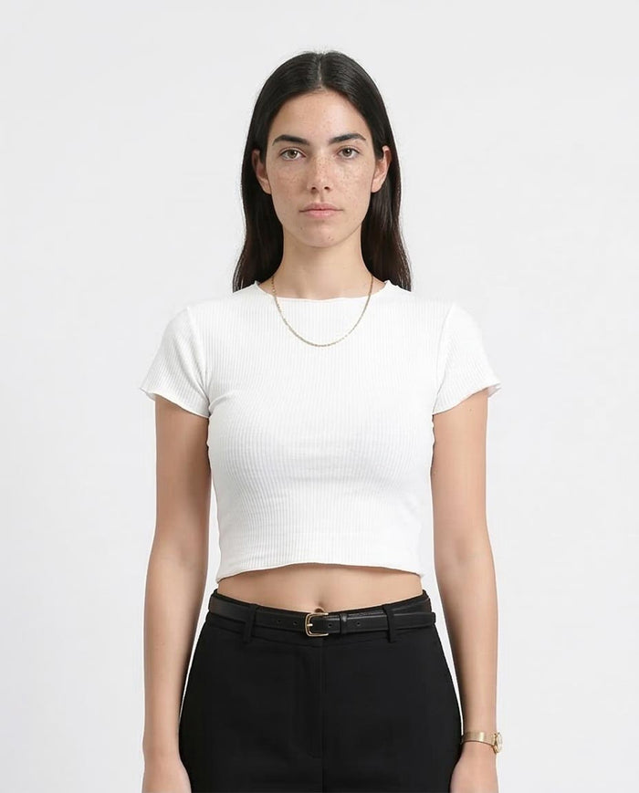 Person wearing a white cropped t-shirt and black pants on a plain background